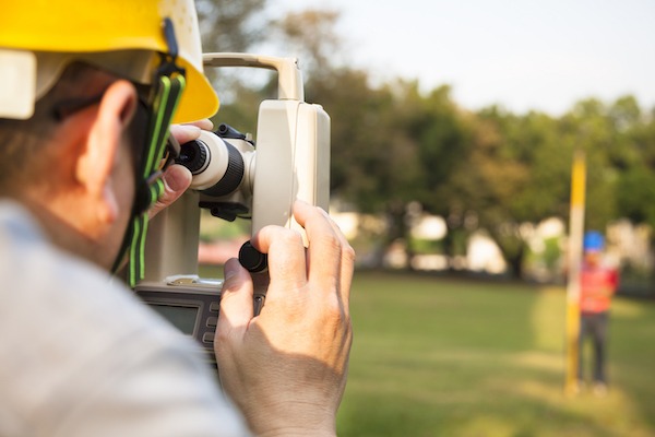 Surveyor engineer with partner making measure on the field